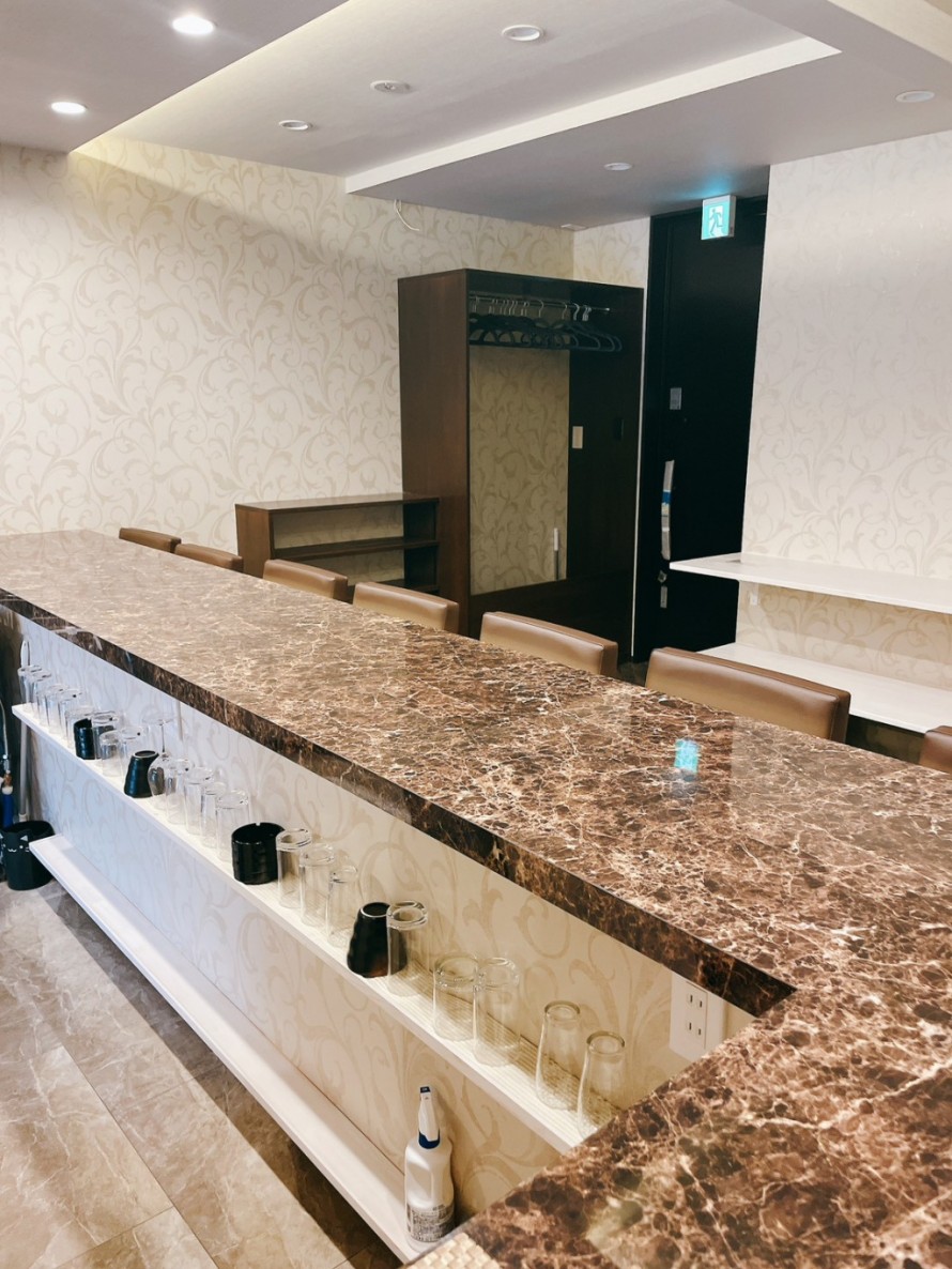 大理石調素材を使用したバーのバーカウンター内装。飲食店デザインの主役となる重厚なカウンター