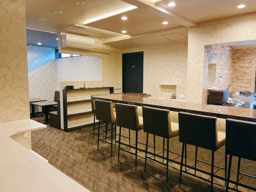 間接照明を取り入れたバーのカウンター席と厨房の内装デザイン。飲食店改装事例