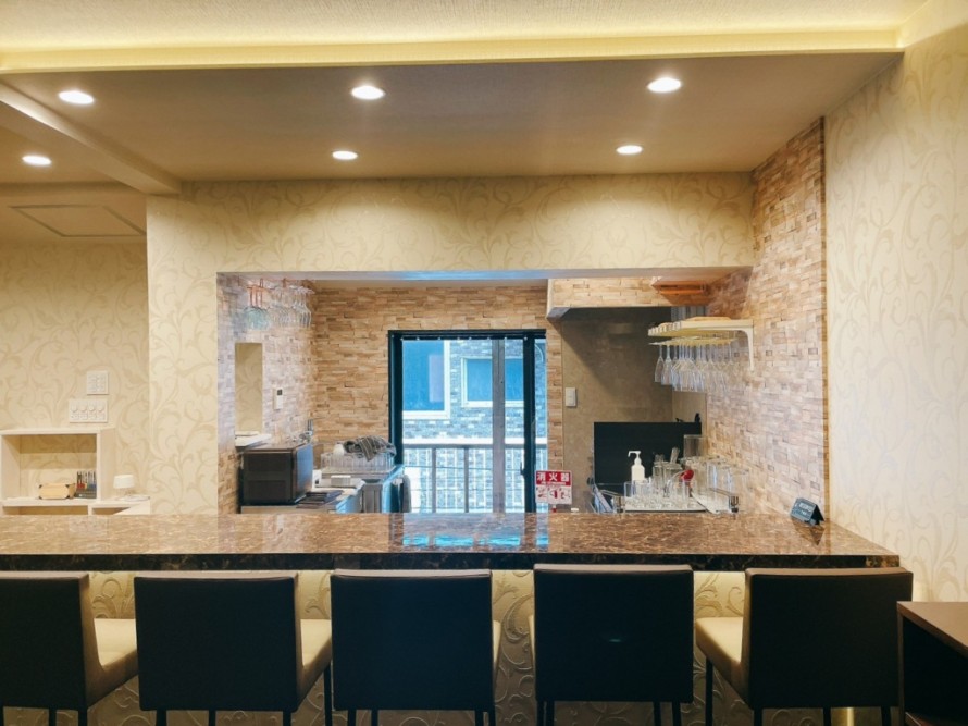 間接照明を取り入れたバーのカウンター席と厨房の内装デザイン。飲食店改装事例