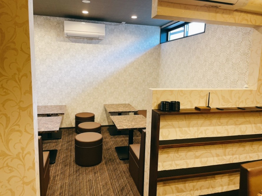 開口を設けたバーのテーブル席内装。飲食店デザインで抜け感を意識した空間