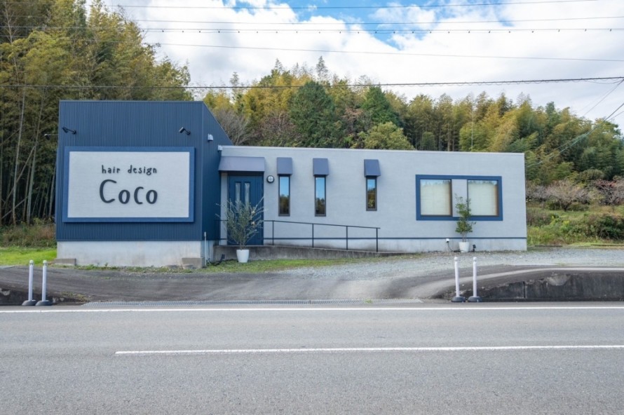 ネイビーのガルバリウム外壁とグレーのジョリパッド塗り壁を組み合わせた美容院の外観デザイン