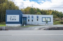 ネイビーのガルバリウム外壁とグレーのジョリパッド塗り壁を組み合わせた美容院の外観デザイン