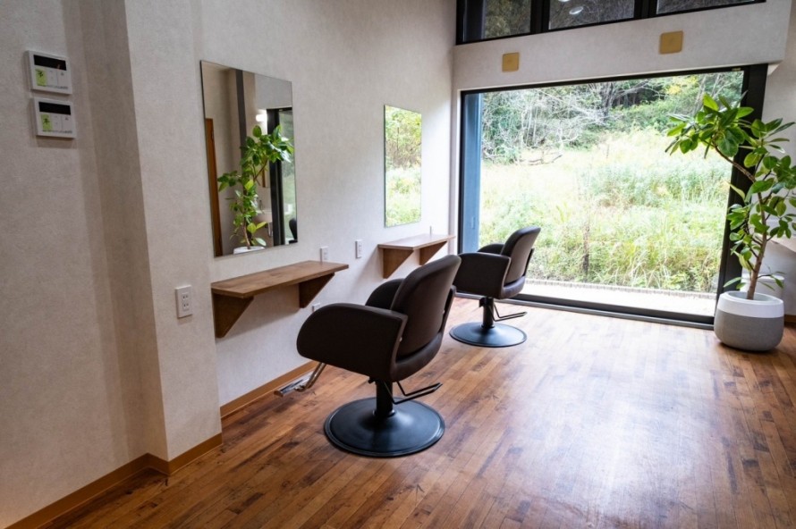 木目調フロアと無垢材風カウンターを備えたシンプルな美容院のカットスペース内装