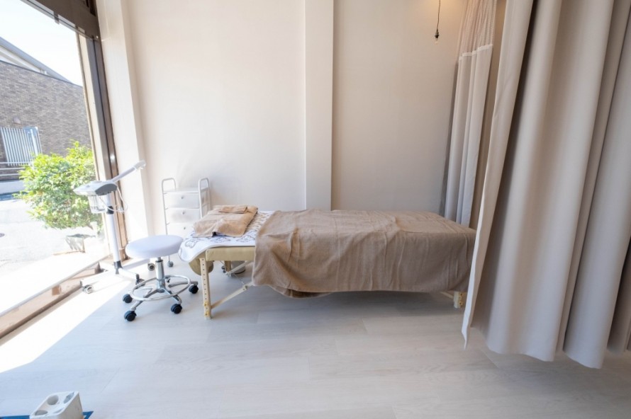大きな窓とカーテンが特徴の明るい施術室内装