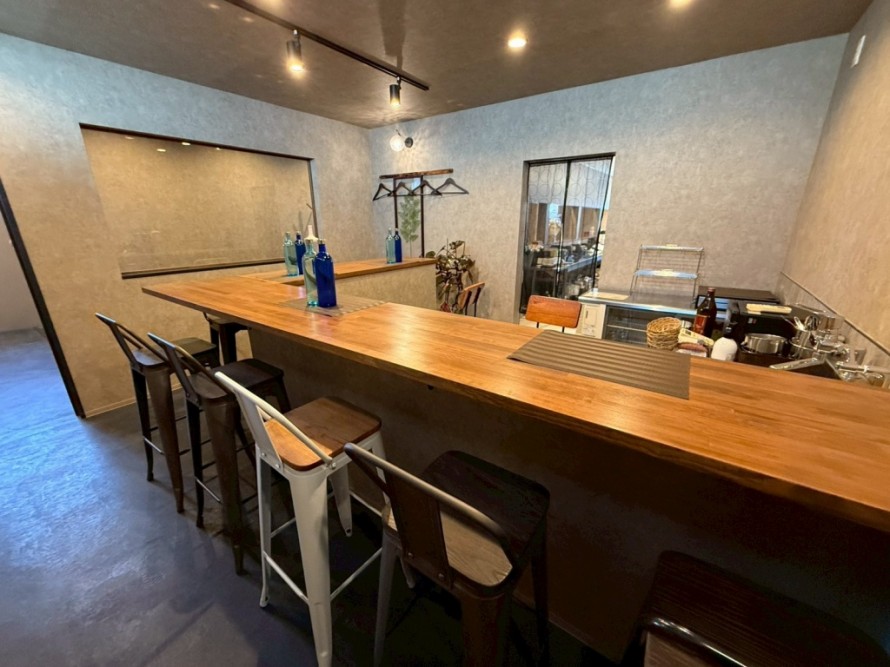 木製バーカウンターと間接照明のある居酒屋内装