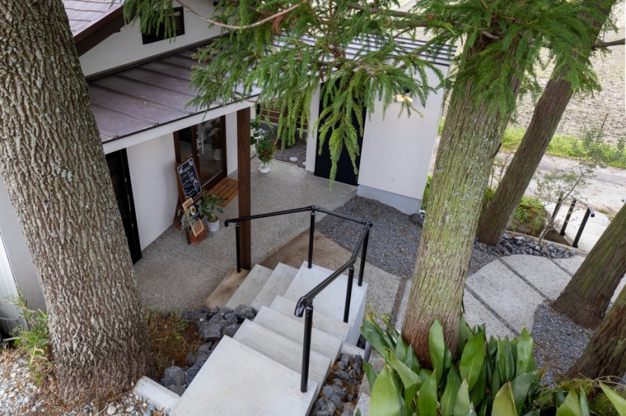 黒い手すり付きコンクリート階段のある隠れ家カフェアプローチ