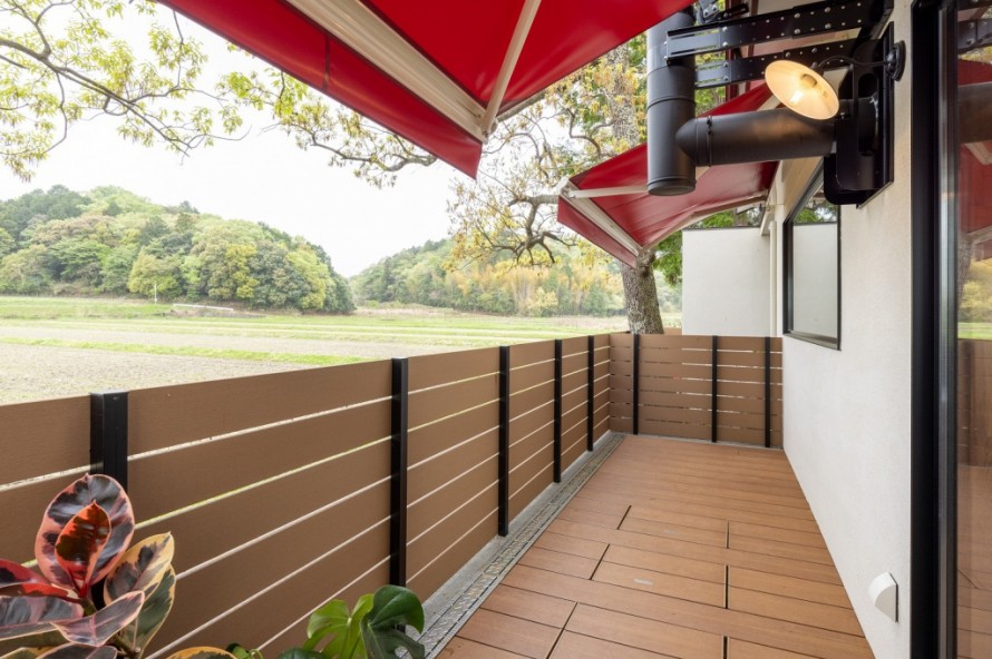 赤いオーニングとウッドデッキのある隠れ家カフェ外観